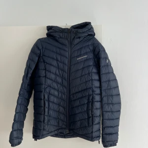 Peak performance jacka mörkblå - En Peak Performance jacka med huva. Perfekt till vintern. Jackan är i damstorlek M, sann till storlek. Har haft den nu i två år och känner för att byta till något nytt. Jackan är i bra skick, har däremot en defekt vid fickan(se bild). 