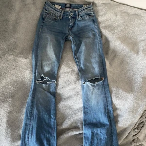 Lågmidjade jeans - Lågmidjade jeans med hål på knäna. Uppsprättade längst ned, passar någon mellan 160-165. (Jag är 165) Stretchiga!