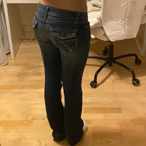 Lågmidjade jeans - Jättesnygga lågmidjade jeans med detaljerade fickor som är för små och därför inte kommer till användning! Midjemåttet: 37 cm rakt över Innerbenslängd: 80 cm (en av knapparna saknas på fickorna kom privat för bildk)