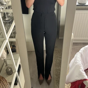 Svarta kostymbyxor - Dam - Svarta kostymbyxor med slits nertill från NA-KD. Stl 32. Kostymfickor baktill. Inga skavanker.