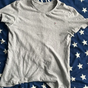 Tommy hilfiger T-shirt  - En grå T-shirt med hål där ner på tröjan framifrån 