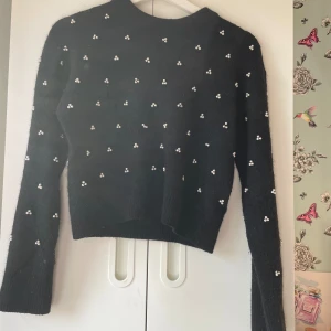 Svart tröja med pärldetaljer från & Other Stories - Säljer en superfin svart tröja från & Other Stories med små pärldetaljer över hela. Den är perfekt för både vardag och fest! Tröjan är i storlek S och har långa ärmar. Materialet är mjukt, man kan uppleva att den sticks lite ibland.Men annars är den👍