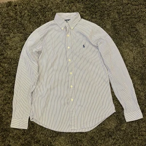 Ralph Lauren skjorta - Säljer denna randiga skjortan från Ralph Lauren då den inte kommer till användning. Skjortan är bara använd ett fåtal gånger och jag skulle säga att skicket är mycket bra. Nypris ligger på runt 1800 men mitt pris är 499. Hör av dig om funderingar