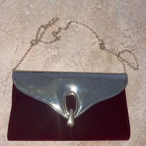 Vinröd kuvertväska med guld detaljer  - En vinröd väska med guld detaljer 