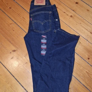 Mörkblå jeans från Levi's - Snygga mörkblå jeans från Levi's med klassisk femficksdesign och kontrastsömmar. Perfekta för en avslappnad stil. Märkeslappen syns tydligt på baksidan. Aldrig använda, st 164. 
