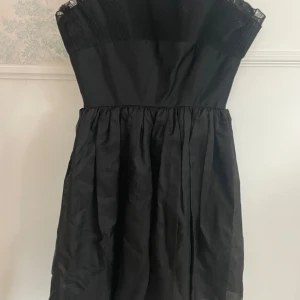 Svart klänning från Polly Peck - Elegant svart klänning i ren silke från Polly Peck. Klänningen har en klassisk design med veckade detaljer upptill och en vid kjol. Perfekt för en stilren look. Skulle säga XS