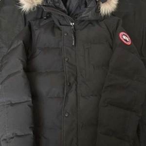Canada goose carson parka - Säljer en svart dunjacka från Canada Goose med pälsdetalj på huvan. Jackan har en dragkedja och knappar framtill samt en broderad logotyp på ärmen. Jackan har legat i förrådet i något år och är i topp skick, kostar cirka 21.000kr i affär men säljs för ett mycket bra pris. Endast seriösa köpare, Äkta såklart!! Pris går att diskuteras vid snabbaffär.