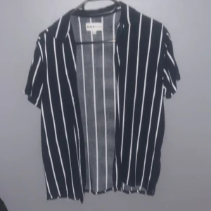 Svart och vit randig skjorta från Zara - Snygg svart skjorta med vita ränder från Zara. Skjortan har korta ärmar och en klassisk krage. Perfekt för en stilren look.