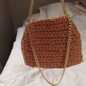 Virkad väska med guldkedja - Trendig virkad väska i en varm rosa nyans med en elegant guldkedja. Perfekt för att ge din outfit en unik touch.