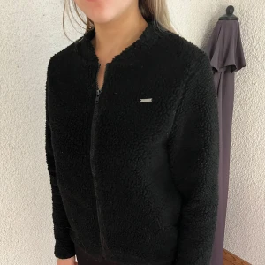 Aim’n Svart Teddyjacka - Storlek small, svart teddy/ fluffigt material. Har inte använt den så mycket. Ganska tunn, passar att ha inomhus på vinter eller utomhus på våren/ hösten 💕+ Säljer en likadan fast beige också! 