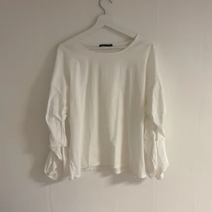 Vit långärmad topp från Coal & Honey - Säljer en stilren vit långärmad topp från Coal & Honey. Toppen har en lös passform och är tillverkad i ett mjukt material. Perfekt för en avslappnad look. Med extra detaljer på ärmarna