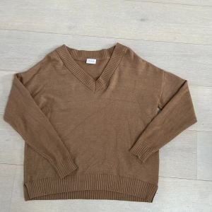 Beigebrun tröja från Vila - Säljer en stilren beigebrun tröja från Vila med v-ringning och ribbade kanter. Perfekt för en avslappnad look.