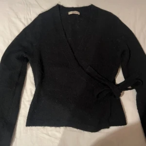 Svart omlottkofta - Säljer den populära svart omlottkofta från Gina i stl M, endast amvänd 2 gånger fortfarande i nyskick. Passar mer en S. Går ej å köpa längre på hemsidan och är slutsåld i alla butiker💕
