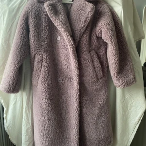 Lila teddyjacka från Monki - Mysig lila teddyjacka från Monki med knappar framtill. Väldigt skön och varm jacka för vintern och våren. Jackan har långa ärmar och två fickor på sidorna. Väldigt bra skick, använd ungefär två gånger. Storlek XXS, passar också XS ev S också.