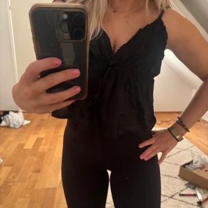 Svart topp - Snygg svart topp med v-ringning och volangdetaljer. Perfekt för en stilren look.