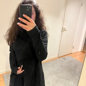 Svart kappa från Only - Snygg svart kappa från Only med en elegant design. Den har långa ärmar och en stilren look som passar perfekt för både höst och vår. Kappan är tillverkad i ett mjukt material och har en öppen front.