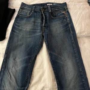 Blå jeans från Replay vintage - Säljer ett par snygga blå jeans från Replay med klassisk femficksdesign och dragkedja. Jeansen har en normal passform och är perfekta för en avslappnad stil. Storlek W29 L32, passar mig som är 180 cm lång