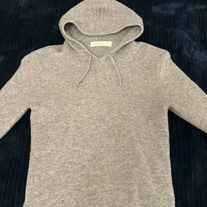 Cashmere hoodie - Mysig grå hoodie i kashmir från Sayless. Perfekt för kyliga dagar med sin mjuka och lyxiga känsla. Tröjan har en klassisk huva med dragsko och långa ärmar.