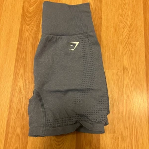 Blå shorts från Gymshark - Blå shorts från Gymshark med hög midja. Sitter uppe ordentligt vid träning! Är väldigt nöjd men enbart använt vid enstaka tillfällen då jag inte är ett fan av shorts. Nya i skicket!