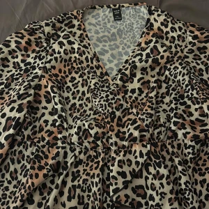 Leopardmönstrad blouse från Shein Curve - Trendig leopardmönstrad blouse från Shein Curve med omlott-design och v-ringning. Perfekt för att sticka ut med stil. Blousen har långa ärmar och en bekväm passform.