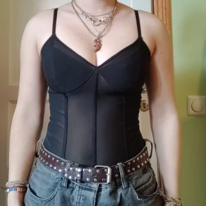 Svart korsett - Snygg svart korsett med smala axelband och formande design. Perfekt för att skapa en stilren och elegant look. Passar bra till både jeans och kjol.
