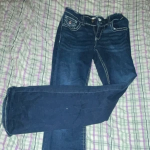 Mörkblå jeans med kontrastsömmar - Snygga mörkblå jeans med vita kontrastsömmar och klassisk femficksdesign. Byxorna har en knapp och dragkedja framtill samt dekorativa sömmar på bakfickorna. Pris kan även diskuteras! 💙 Dessa kan vara stora i storleken men kan justeras i midjan. 