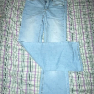 Ljusblå jeans - Säljer ett par ljusblå jeans med klassisk femficksdesign. De har en rak passform och är perfekta för en avslappnad stil. Jeansen har en dragkedja och knapp framtill. Bootcut med mid waist 