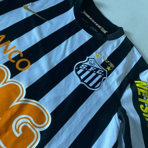 Santos fotbollströja neymar 11 - Snygg randig fotbollströja från Nike med svart och vitt mönster. Tröjan har neymar 11 på ryggen från tiden han spelat i santos, den klassas som en ikonisk tröja nu för tiden. Använd max 2-3 gånger, lite stor i storleken.