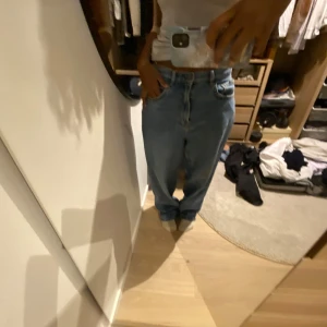 Blå jeans med hög midja - Säljer ett par blå jeans med hög midja och avslappnad passform. Perfekta för en casual look. De har klassiska fem fickor och en knappgylf.