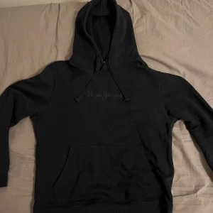 Marinblå hoodie från Pepe Jeans - Tja, säljer en stilren marinblå hoodie från Pepe Jeans med broderad logga på bröstet. Den har en klassisk känguruficka och justerbar luva. Perfekt för en avslappnad look. Pris går att diskutera!