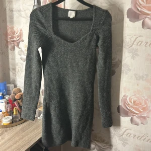 Grå stickad klänning - Snygg grå stickad klänning med långärmad design och fyrkantig halsringning. Perfekt för kyligare dagar med sin mysiga och stilrena look. Passar bra till både vardag och mer uppklädda tillfällen.