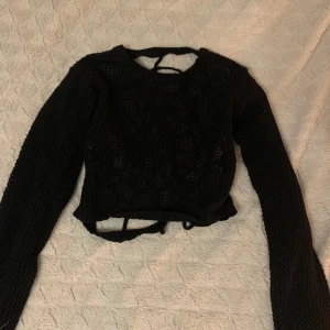 Svart stickad tröja med spindelnätsmönster - Säljer en unik svart stickad tröja med ett coolt spindelnätsmönster på ryggen. Tröjan är croppad och har långa ärmar:)