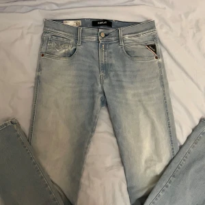 Ljusblå jeans från Replay - Snygga ljusblå jeans från Replay i modellen Anbass. De har en klassisk femficksdesign och är tillverkade i ett bekvämt denimtyg. Byxorna har en naturlig slitning men inget som påverkar utseendet negativt snarare så blir det snyggare. Storlek är 30/32. Jag är 180cm och jeansen är bra i längd.