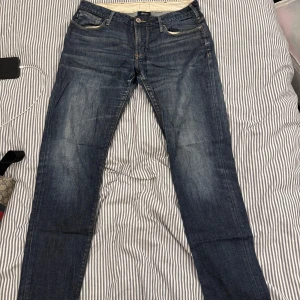 Blå jeans från Armani - Snygga blå jeans från Armani med klassisk femficksdesign och subtila slitningar. De har en normal passform och är perfekta för en avslappnad stil. Märkeslogga på bakfickan ger en extra touch av stil.