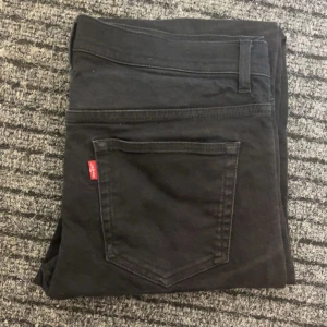 Svarta jeansbyxor från Levi's - Snygga svarta jeansbyxor från Levi's med klassisk design och röd etikett på bakfickan. Perfekta för en stilren look.