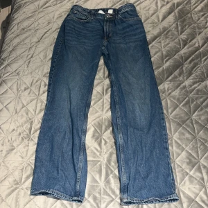 Blå jeansbyxor - Säljer ett par klassiska blå jeansbyxor med normal passform. Byxorna har en rak stil och är utrustade med både fram- och bakfickor samt en dragkedja och knapp framtill. 