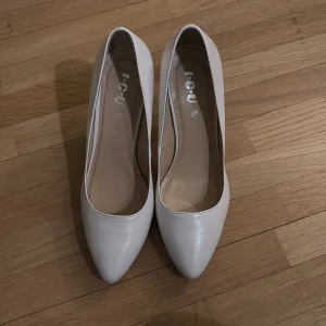 Vita pumps med klack - Eleganta vita pumps från I.C.U i storlek 39. Skorna har en spetsig tå och hög klack, vilket ger en stilren och klassisk look. Perfekta för att lyfta din outfit till nästa nivå.