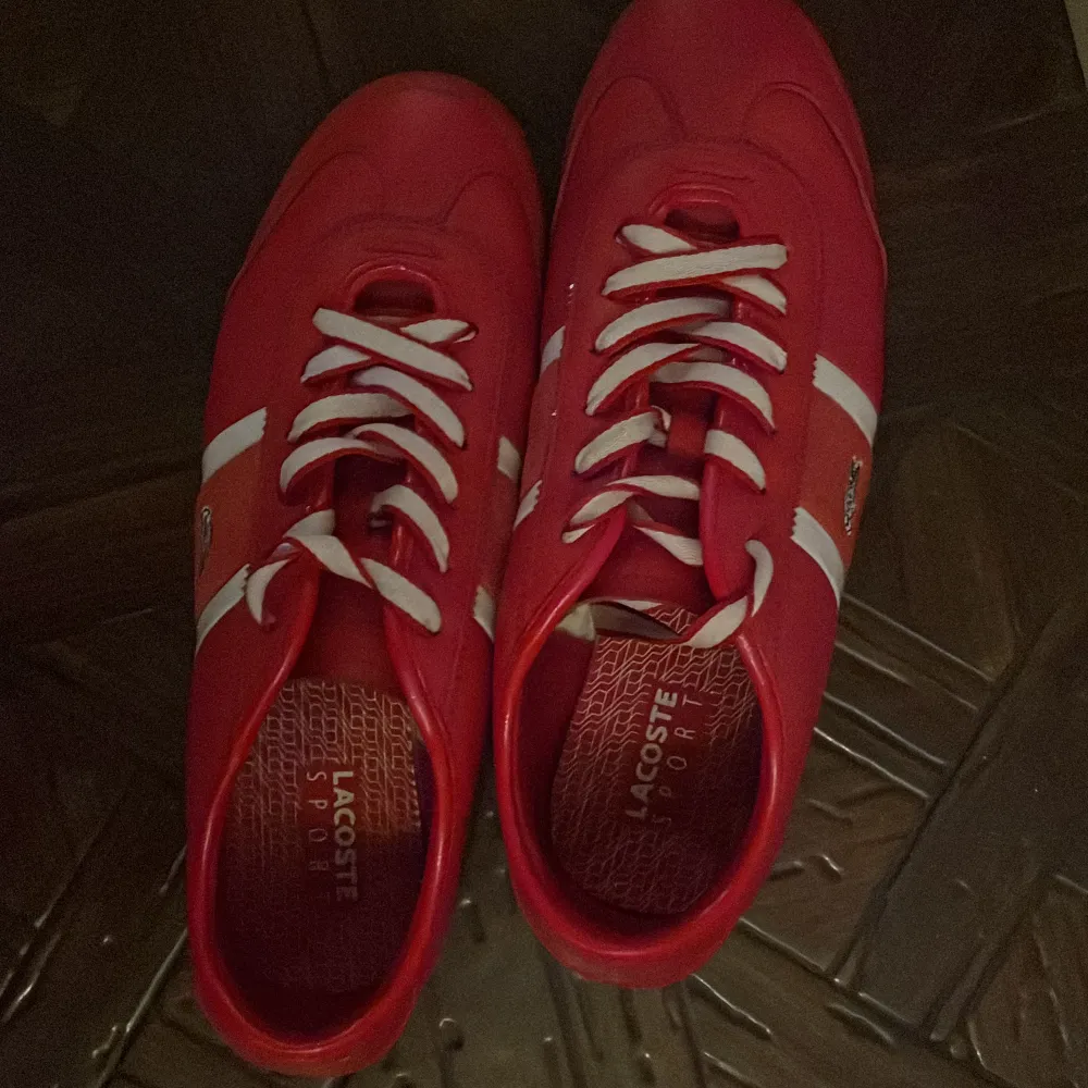 Snygga röda sneakers från Lacoste med vita detaljer och snörning. Skorna har en sportig design med Lacoste-logga på sidan och mönstrad sula för bra grepp. Perfekta för en casual look. Kontakta mig för minsta lilla fundering pris kan diskuteras OBS Har inte kvitto eller box för skorna är köpta för länge sedan. Kengät.