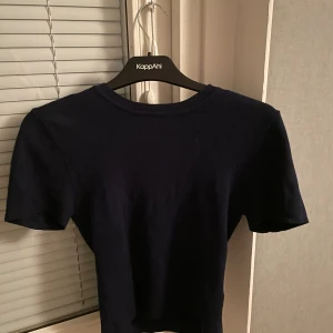Mörkblå topp från Gina Tricot - Säljer en stilren mörkblå topp från Gina Tricot. Toppen har korta ärmar och en rund halsringning, perfekt för en enkel och snygg look. Passar bra till både jeans och kjol. Orginal priste är 299 plus använt 1 gång 