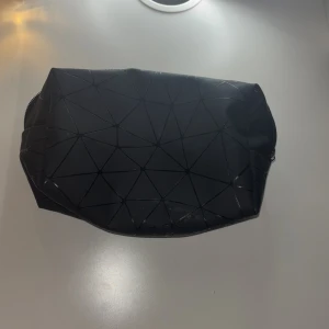 Svart geometrisk necessär - Snygg svart necessär med geometriskt mönster och dragkedja. Perfekt för att organisera dina småsaker. Stilren design som passar alla tillfällen.