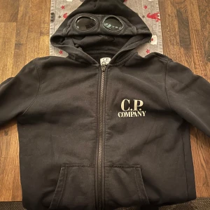 Svart hoodie från C.P. Company - Snygg svart hoodie från C.P. Company. Använt skick men fortfarande fräsch!