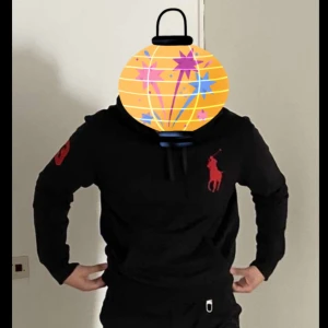 Svart hoodie från Ralph Lauren - Snygg svart hoodie från Ralph Lauren med röd logga på bröstet och ärmen. Perfekt för en avslappnad stil med en klassisk touch. Passar bra till både jeans och träningsbyxor. För stor för mig då jag gått ner till M 