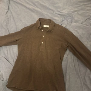 Brun pikétröja från John Henric - Säljer en stilren brun pikétröja från John Henric. Tröjan har långa ärmar och knappar framtill. Perfekt för en avslappnad men ändå snygg look. Perfekt för en middag eller en vardags outfit. Används max 4 gånger så skicket kan inte vara bättre än 10/10 nypris 1300