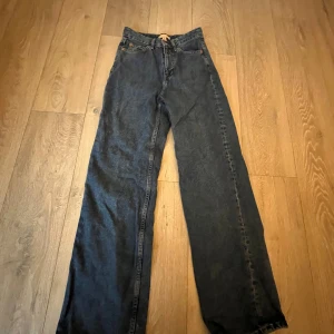 Blå jeansbyxor från H&M - Snygga blå jeansbyxor från H&M med en klassisk design. Byxorna har en rak passform och är perfekta för en avslappnad stil. De har fickor både fram och bak samt en knapp och dragkedja i gylfen.