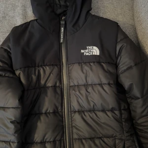 Svart dunjacka från The North Face - Säljer denna snygga jacka från The North Face med dragkedja och huva. Logotypen syns tydligt på bröstet och ryggen. Den är i jättefin skick:) priset går att diskutera. 
