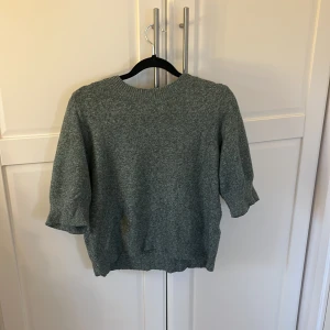 Grön stickad tröja - Säljer en mysig grön stickad tröja med rund hals och trekvartsärmar. Perfekt för kyligare dagar och enkel att matcha med olika outfits. Tröjan har en avslappnad passform och ribbade kanter.
