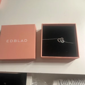 Silverhalsband från Edblad - Silverhalsband från Edblad med en fin detalj i form av två sammanlänkade ringar. Halsbandet har en justerbar kedja och stängs med en karbinhake. Säljer pg av att jag inte använder silver längre, knappt använt det💕original pris: 449 kr