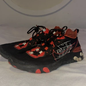 Nike skor - Snygga svarta sneakers med röda detaljer och en unik vit design på sidan. Skorna har snörning och en bekväm sula med runda mönster. Perfekta för en cool och avslappnad stil. Storlek 42,5 eur