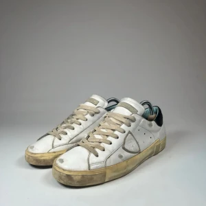 Philippe Model PSRX  - Snygga vita sneakers från Philippe Model. Skorna har en smutsig look med beige sula och snörning.                 Skick: 3,5/5.                                                                             Kommer med orginal box.