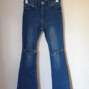 Jeans - Snygga blå bootcut jeans med slitningar på knäna. De har en hög midja. De är knappt använda och är i storlek 26/30